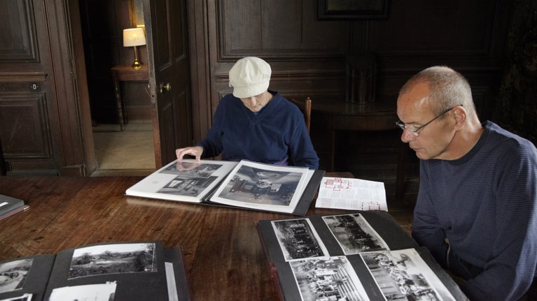 Two people sitting down looking at photograph albums at Chastleton House, Oxfordshire